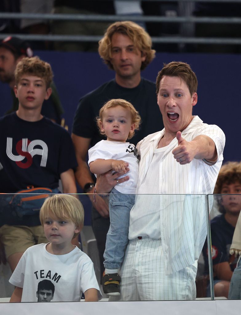 Dustin Lance Black with a thumbs up holding his son Phoenix