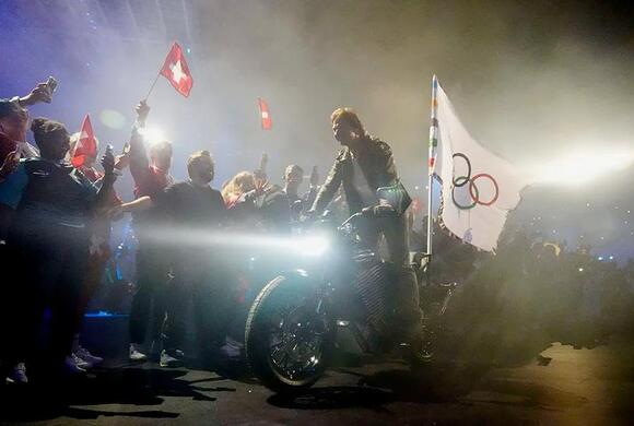 Tom Cruise rides a motorcycle out of the stadium with the Olympic flag during the closing ceremony for the Paris 2024 Olympic Summer Games at Stade de France.