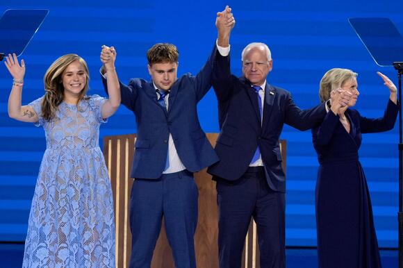 Hope, Gus, Tim and Gwen Walz stand hand in hand on stage