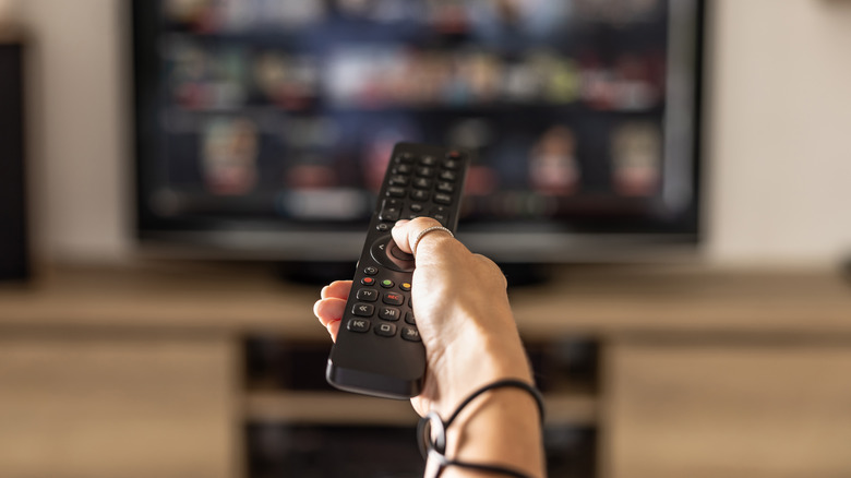 Person pointing remote at TV