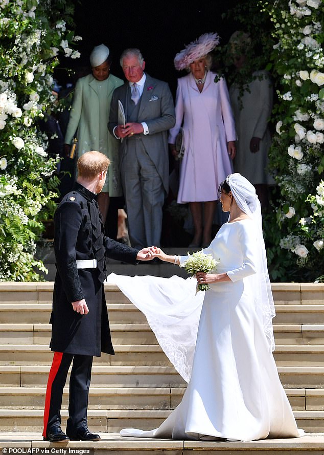 Prince Harry and Meghan on their wedding day looking back towards their family as Doria, Charles, and Camilla leave the chapel