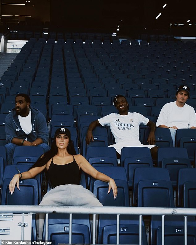 Another picture showed her sitting in the empty stands with the guys, Junior and her two friends, with her arms and legs spread widely in a power pose